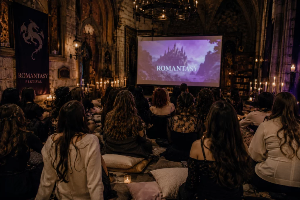Plusieurs personnes regardent un film romantasy sur un écran