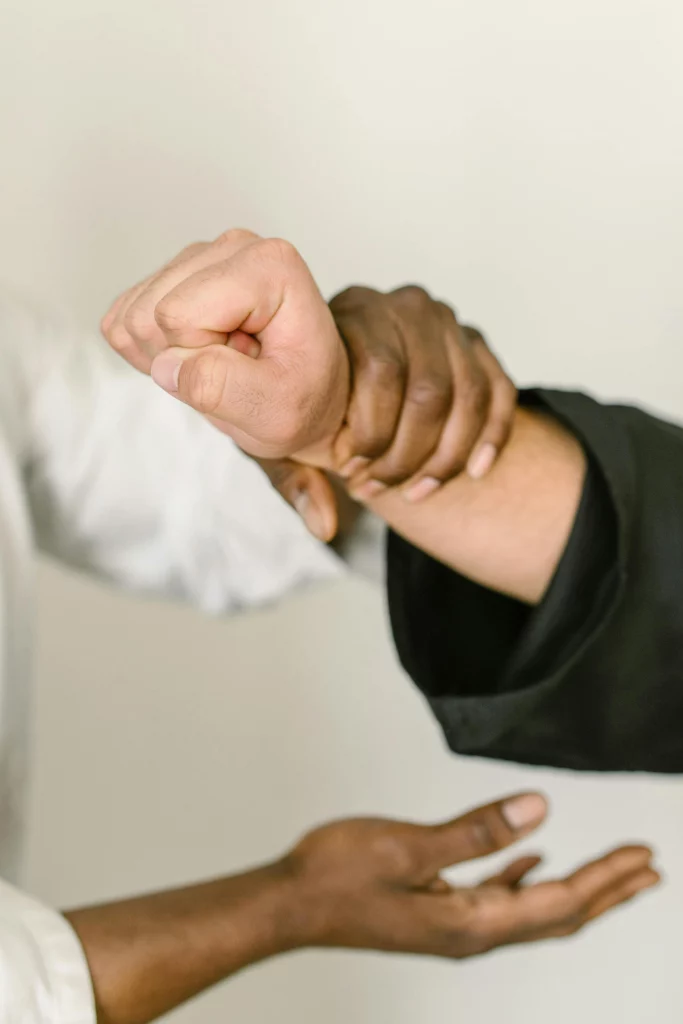 Photo représentant le cours de self défense, deux personnes se tiennent les mains en tenue de karaté